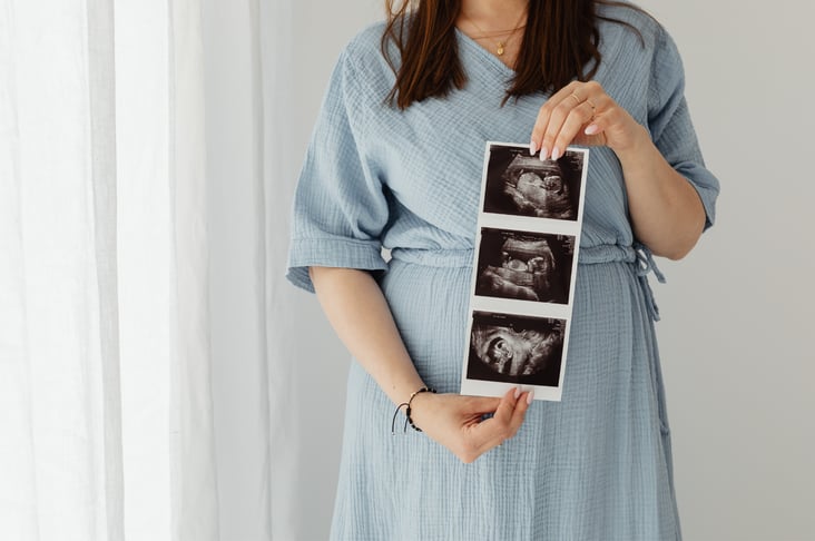 Pregnant woman holding ultrasound announcing pregnancy via donor eggs over 40.