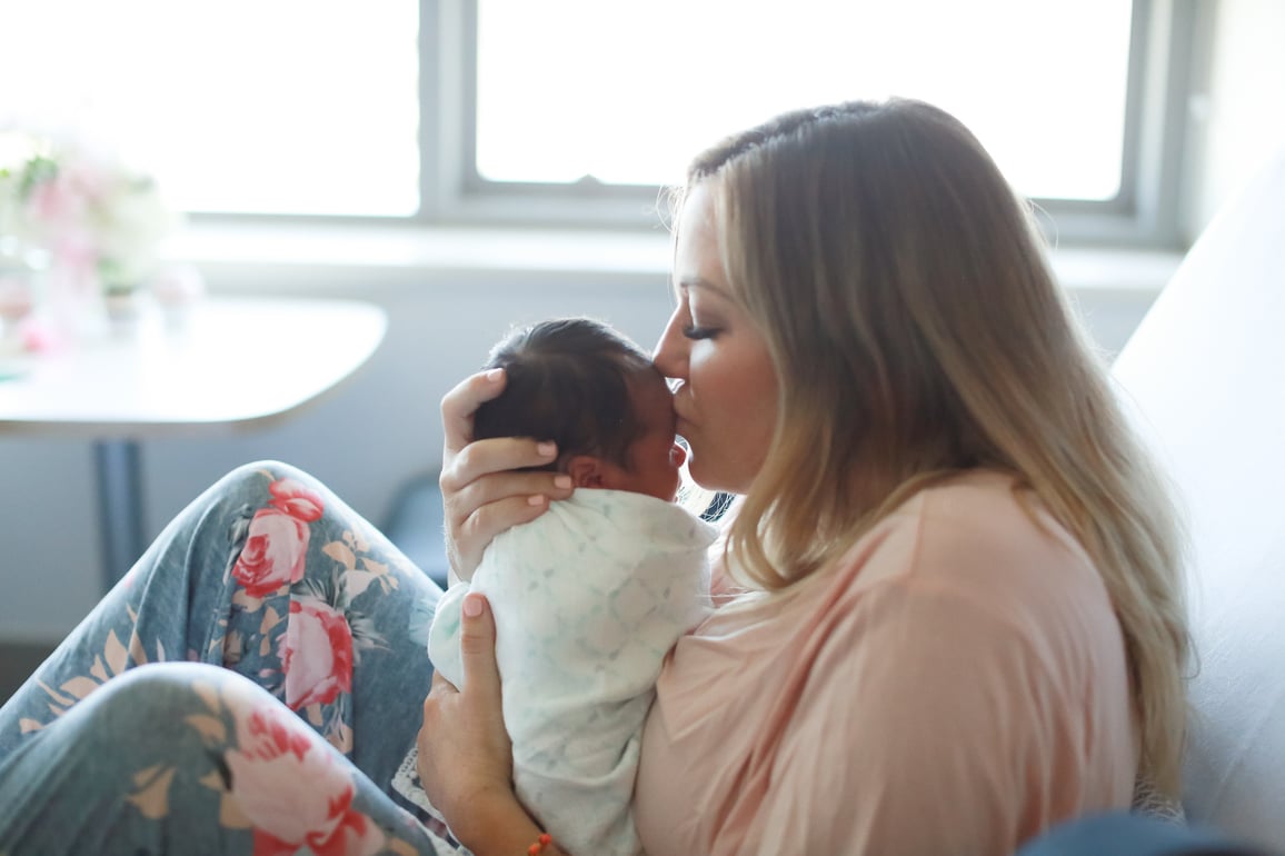 Woman kissing baby born via egg donation, wondering 